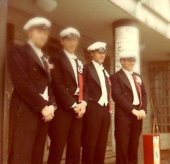 Fire mannlige studenter med studerlue oppstilt på rekke.