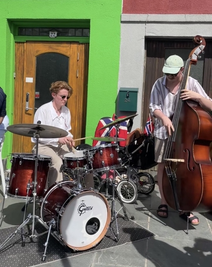 En gruppe musikanter spiller langs veien i sentrum på 17. mai. En spiller trommer og en spiller kontrabass. 