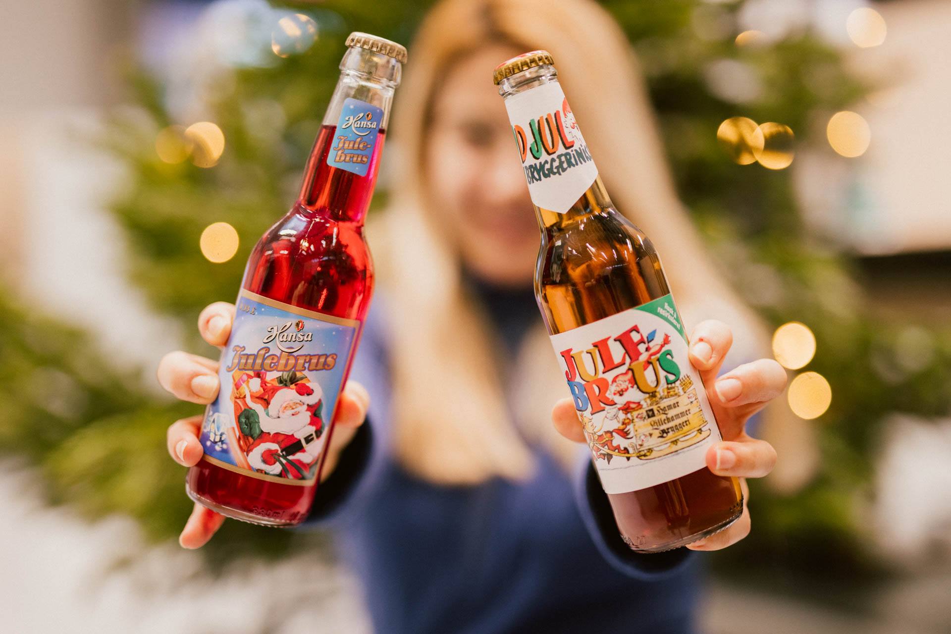 A person holds up two bottles of Christmas soda.