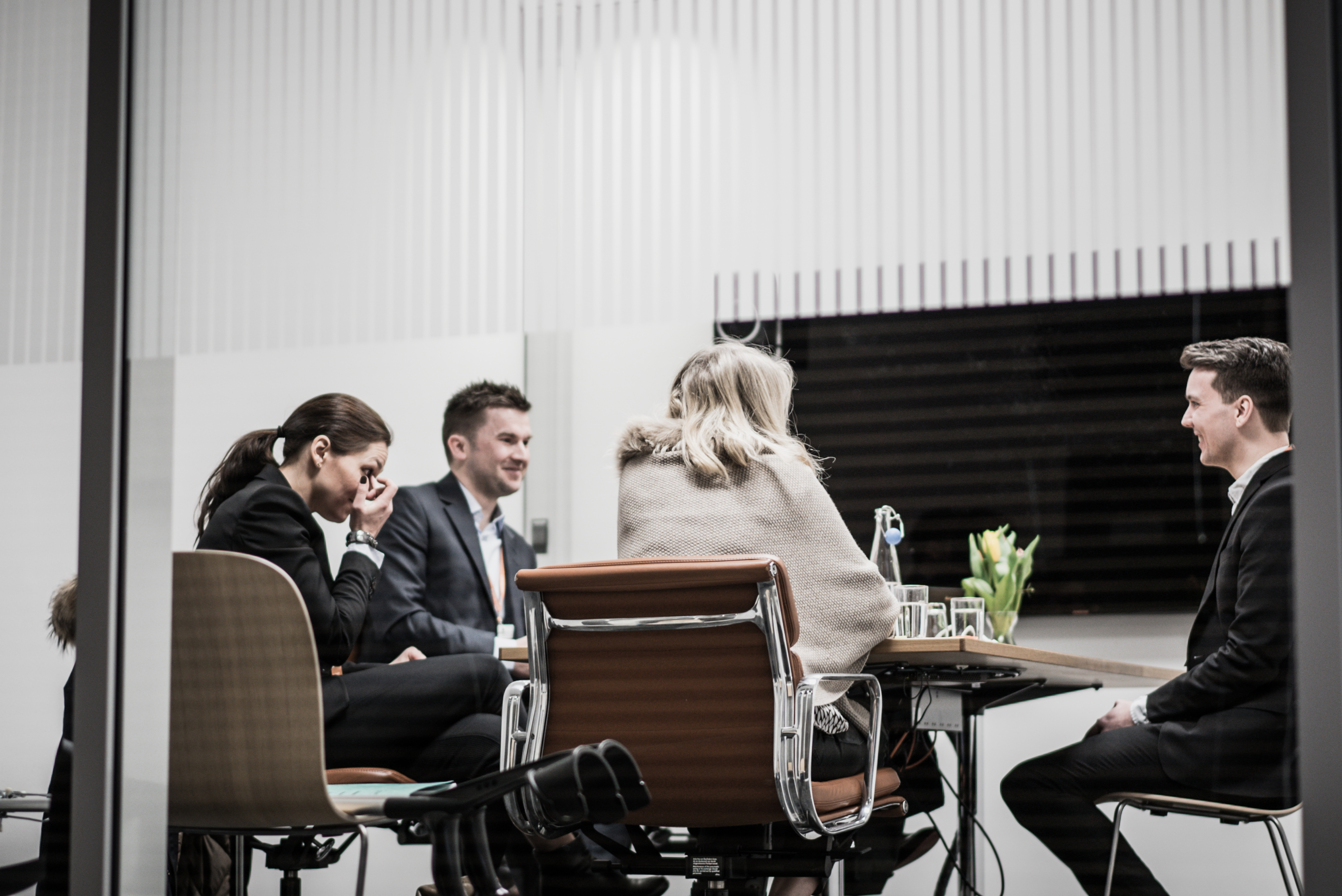 Fire personer rundt et møterom.