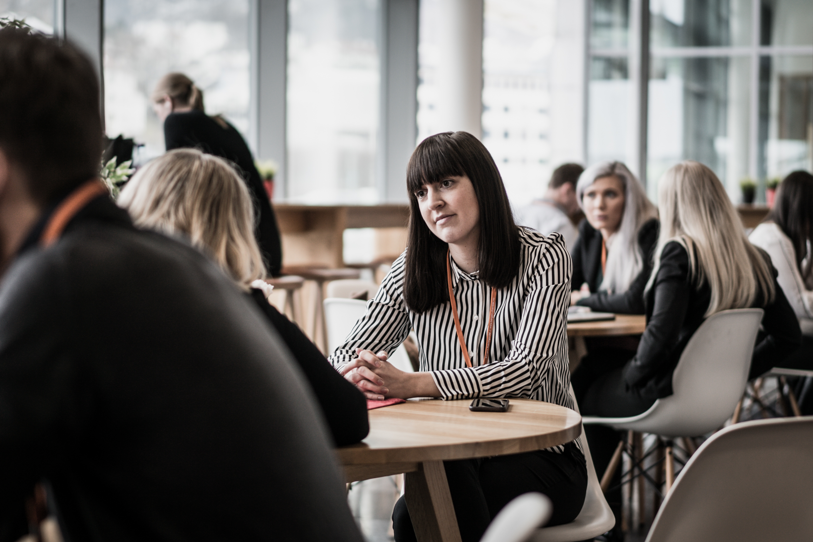 Student i samtale med en annen person rundt et bord i et folksomt lokale.