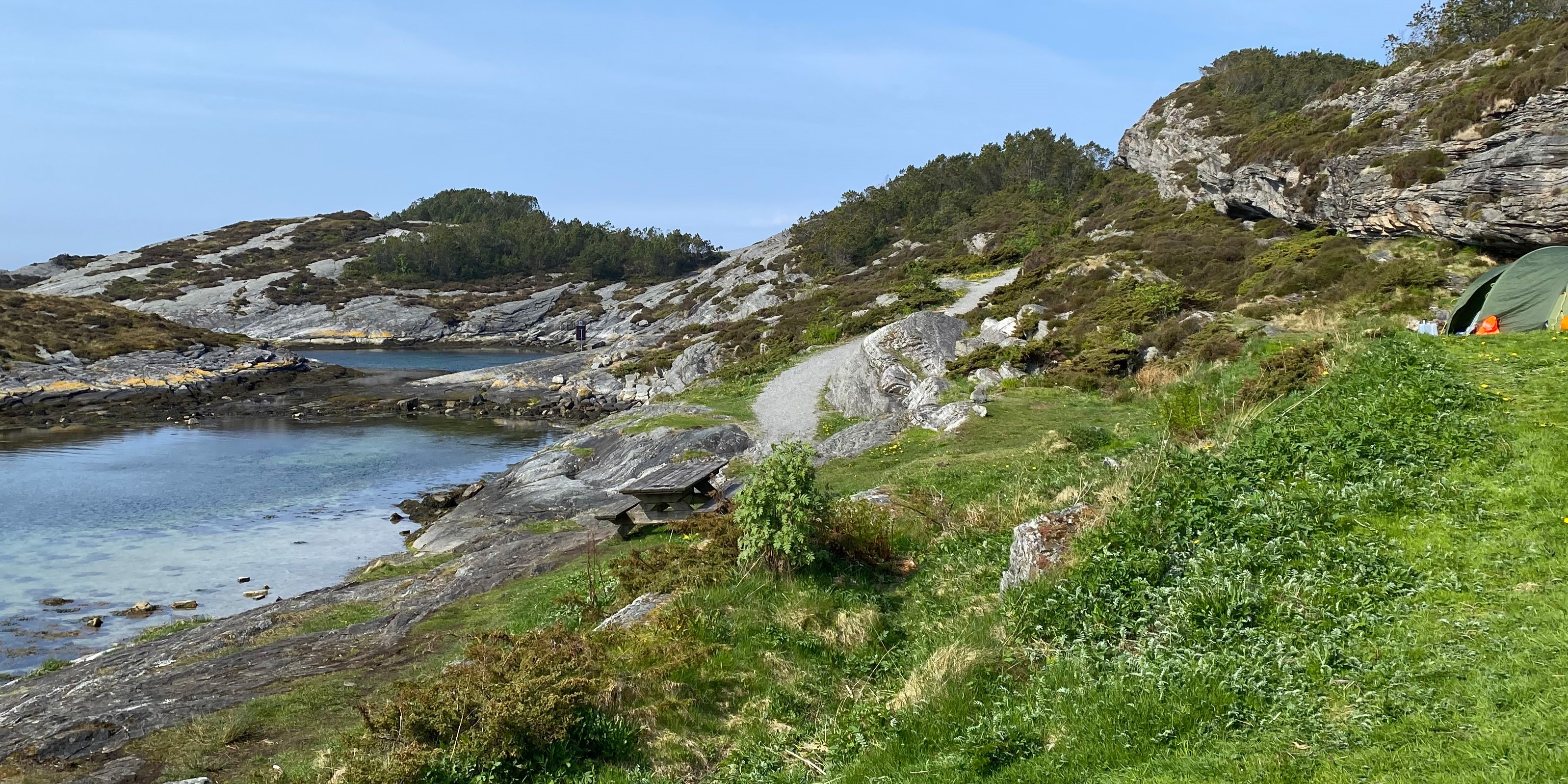 Bilde av et telt omringet av skog og sjø i Ormhilleren