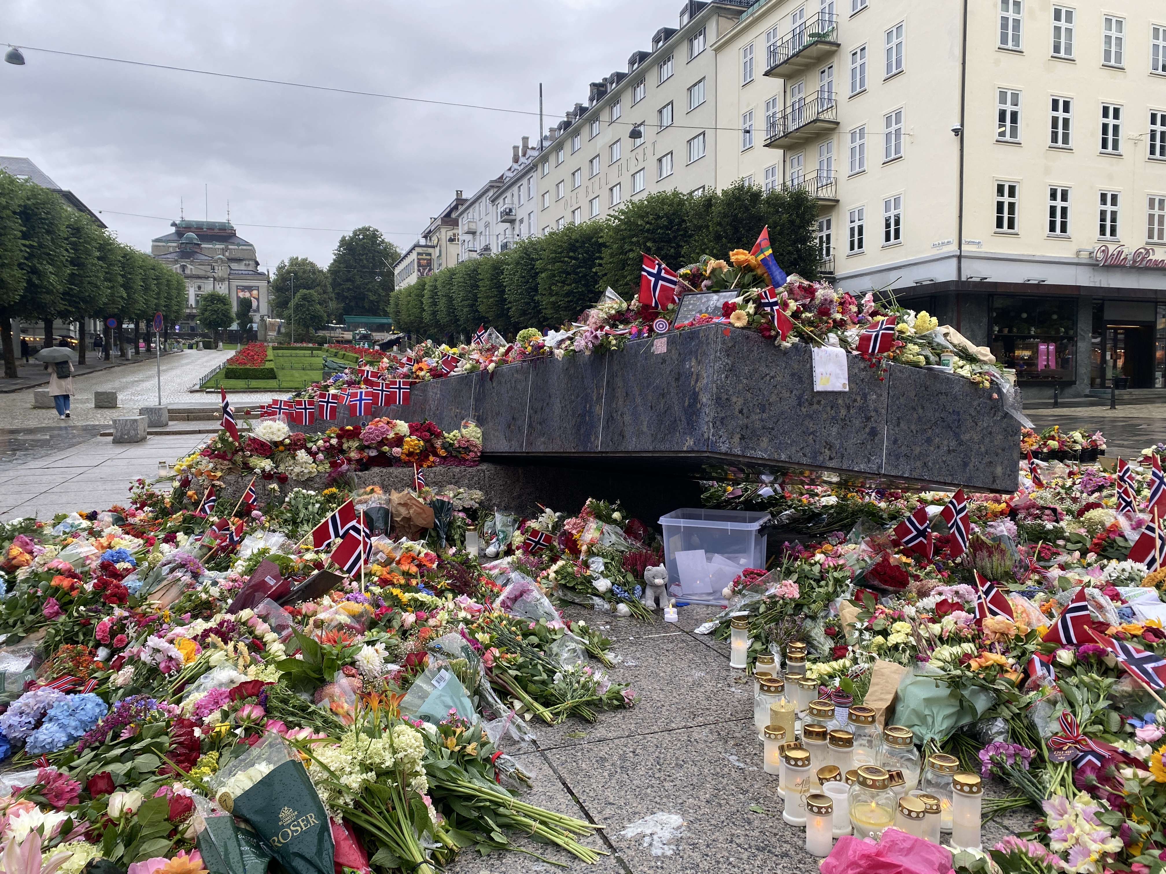 Bilde av den blå steinen på en gråværsdag hvor steinen er dekket med blomster i forbindelse med minnemerkering