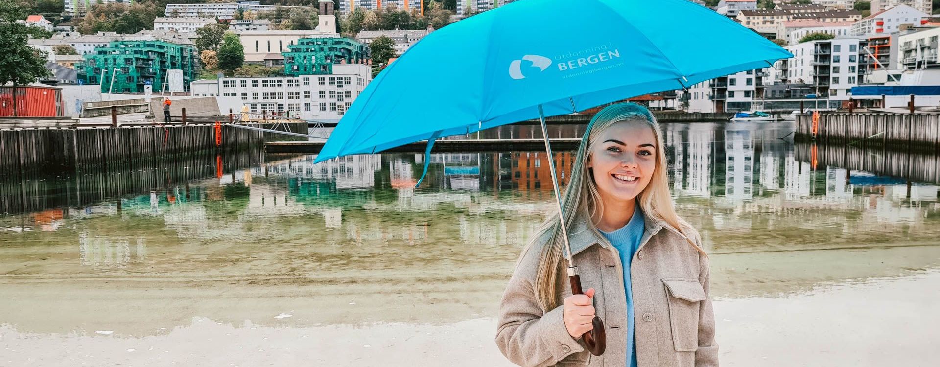 Student with an umbrella on a beach in Bergen city center. 