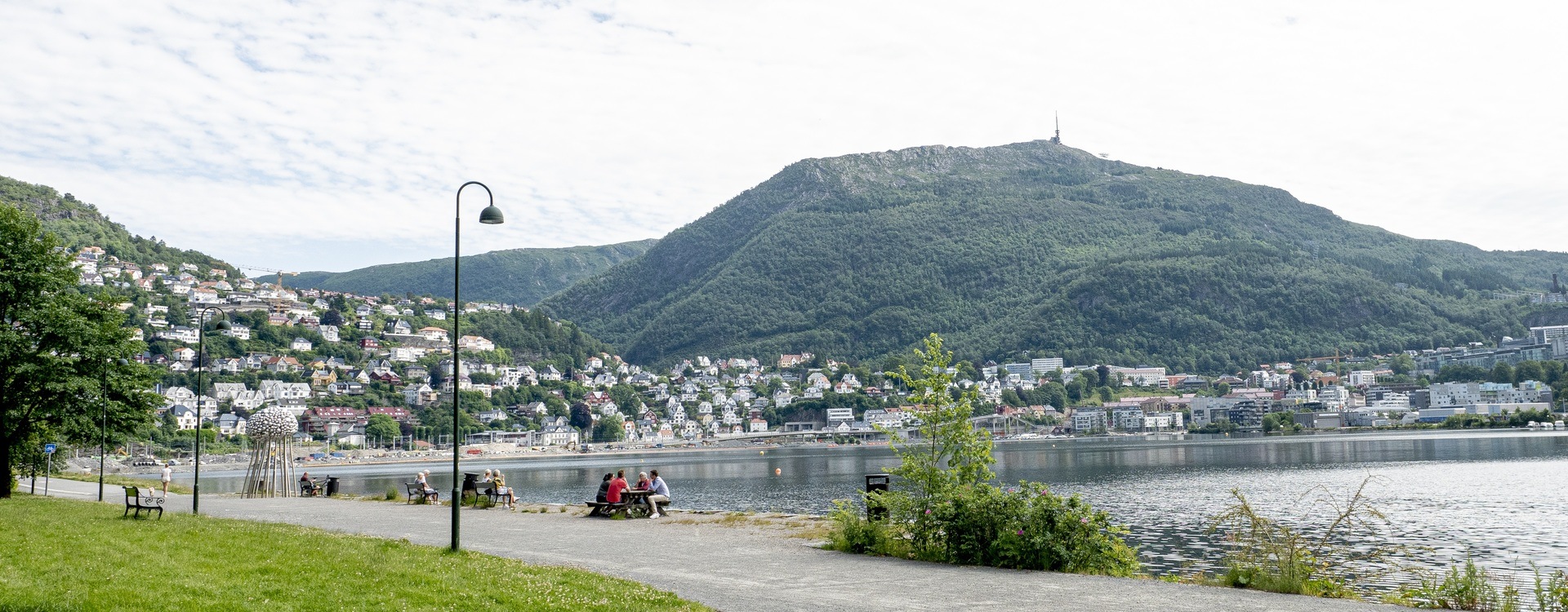 Store Lungegårdsvannet with Mount Ulriken in the background. People walking along the seafront.