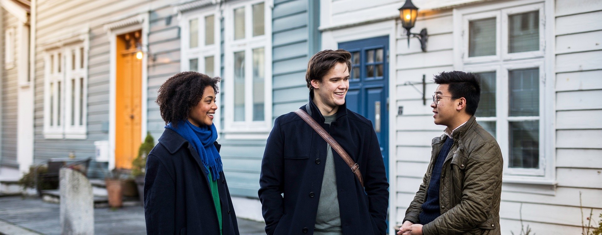 Three students talking together in front of a student house in a Bergen street.