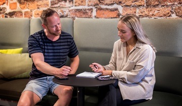 To personer sitter i en sofa og jobber på et dokument. Foto. 