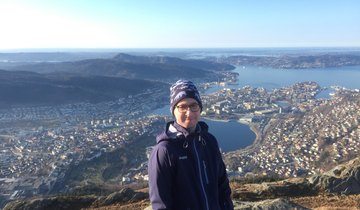 Tommy på toppen av et byfjell med Bergen i bakgrunnen. 