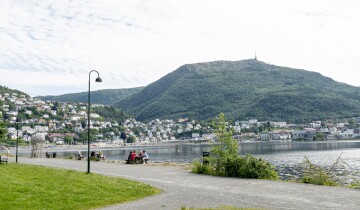 Store Lungegårdsvannet with Mount Ulriken in the background. People walking along the seafront. 