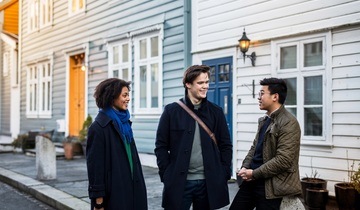 Three students talking together in front of a student house in a Bergen street.
