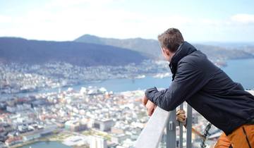 Mann med ryggen til som ser på utsikt over Bergen fra Fløyen. 