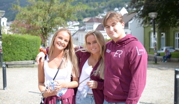 Tre faddere ser i kamera og smiler.