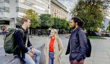 Three students sitting on the Blue Stone. Photo