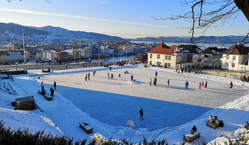 View over Skansedammen in good weather with people ice skaing.